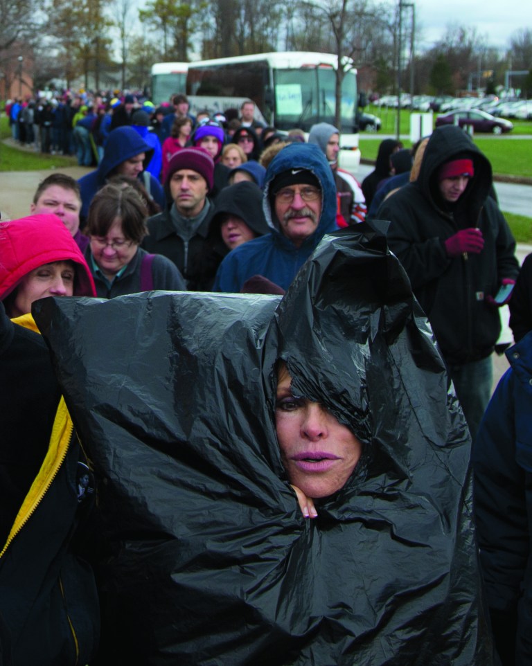 Justine Ovsenik of Willoughby Hills, Ohio, struggles to stay warm with the help of a trash bag as she waits in line to enter Mentor High School to hear President Barack Obama speak at a campaign event, Saturday, Nov. 3, 2012, in Mentor, Ohio, before he travels to Milwaukee for another Campaign event. (AP Photo/Carolyn Kaster)