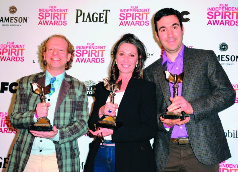 Producers Bruce Cohen, left, Donna Gigliotti, and Jonathan Gordon, right, pose backstage with the award for best feature for 