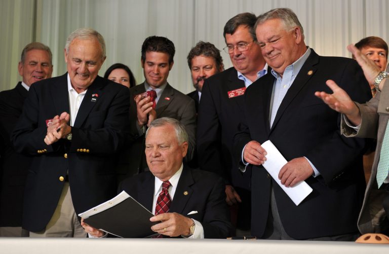 Georgia Gov. Nathan Deal, seated, has signed a $42.4 billion state operating budget, with improving revenues allowing the state to increase public education spending by hundreds of millions of dollars. (AP Photo/Atlanta Journal-Constitution, Brant Sanderlin)