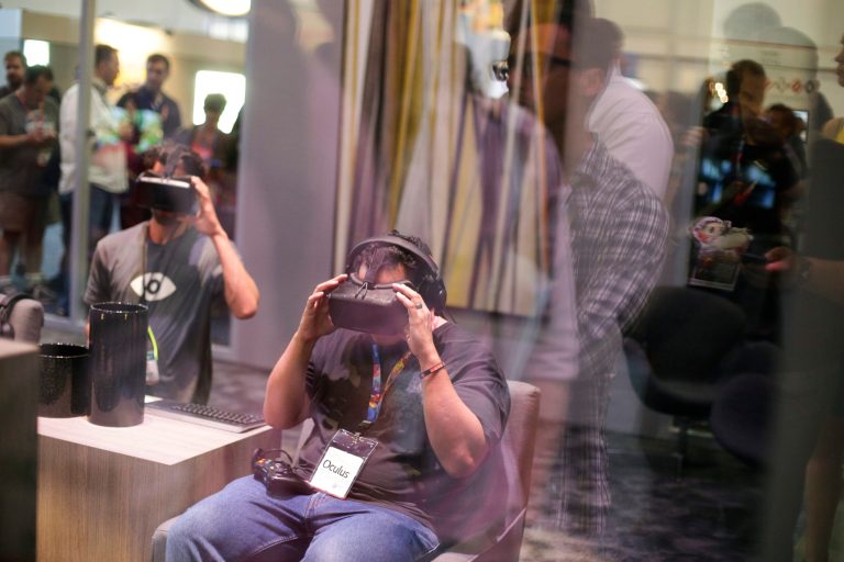 A man tries out the Oculus Rift virtual reality headset as show attendees wait in line outside the Oculus booth at the Electronic Entertainment Expo on Wednesday, June 11, 2014, in Los Angeles. (AP Photo/Jae C. Hong)