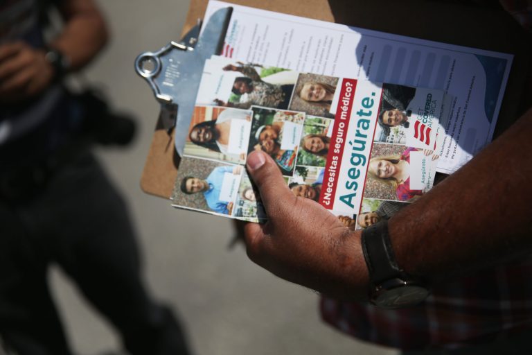 A volunteer shows a passerby information on how to sign up for coverage under the Affordable Care Act, also known as Obamacare. (Joe Raedle/Getty Images)