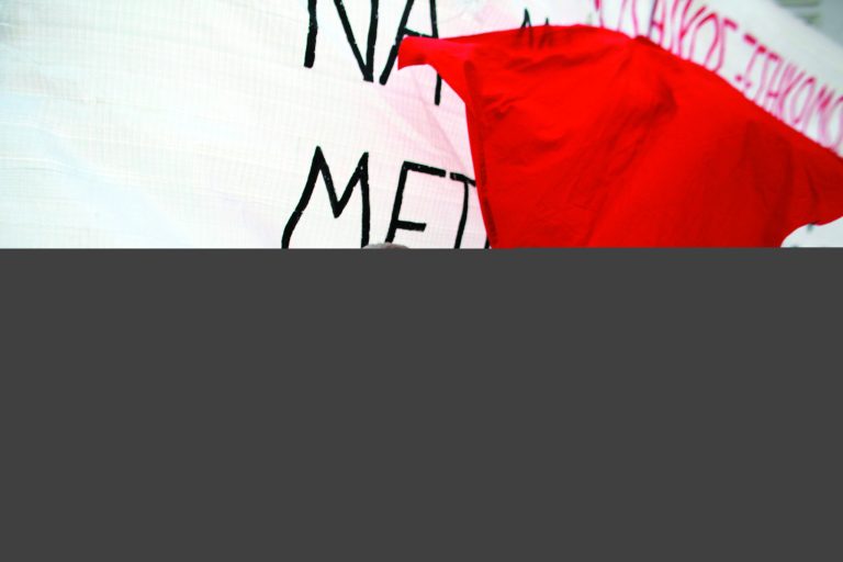A protester stands in front of a banner during a rally in Athens on Saturday, Nov. 17, 2012. Several thousand marchers are commemorating the 39th anniversary of a deadly student uprising against the then ruling dictatorship, with more than 6,000 police deployed in the center of the Greek capital. (AP Photo/Kostas Tsironis)