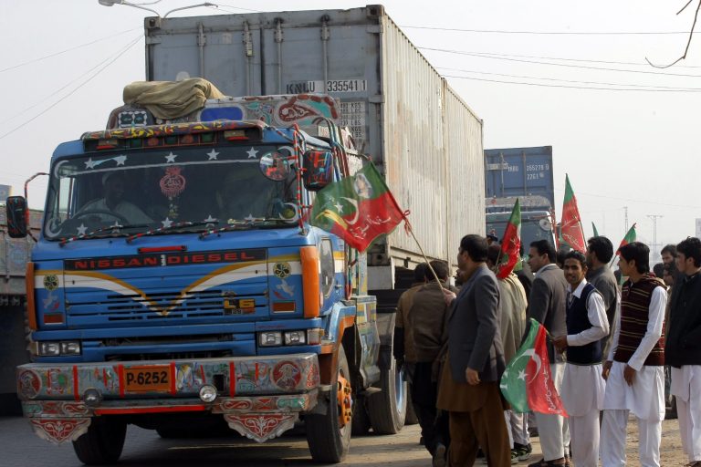 In this photo taken on Monday, Dec. 16, 2013, workers of Pakistan Tehreek-e-Insaf  check private containers on their way to neighboring Afghanistan in Peshawar, Pakistan. Tehreek-e-Insaf, headed by cricketer-turned politician Imran Khan, has stopped movement of NATO containers to Afghanistan which has frustrated the U.S. officials. (AP Photo/Mohammad Sajjad)