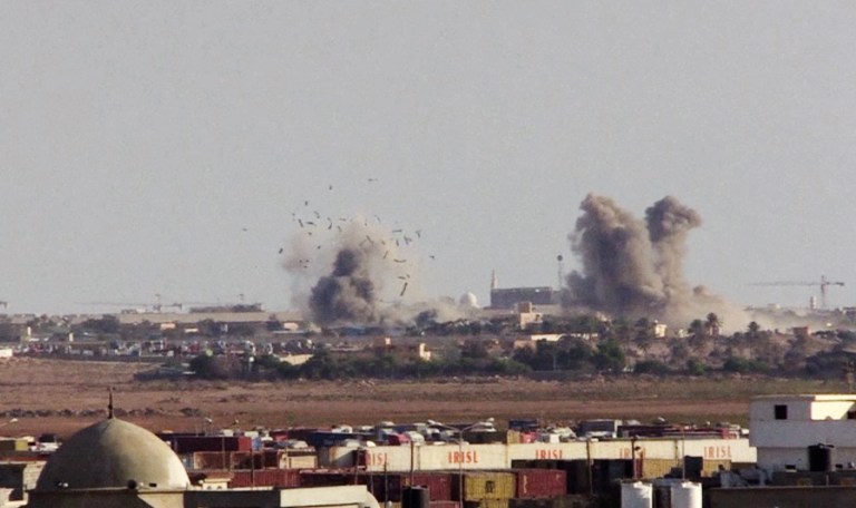 In this image made from AP video on Friday, Aug. 1, 2014, plumes of smoke and debris rise from a base of Islamic militias after a MiG fighter jet's strike in Benghazi, Libya. MiG fighter jets, reportedly under the control of renegade general, Khalifa Hifter, struck in retaliation the bases of Islamic militias in Benghazi on Friday, as a coalition of Islamic militias over the past week captured a number of army bases in Benghazi, driving out troops and police and seizing large weapon stores. (AP Photo/AP video)