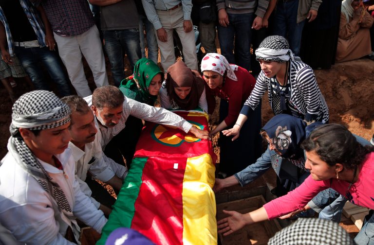 Mourners lower the coffin bearing the body of Mizgin Culbakge, a female Kurdish fighter killed in clashes with militants of the Islamic State group in Kobani, Syria, during the funeral of four female fighters, at a cemetery in Suruc, on the Turkey-Syria border, Tuesday, Oct. 14, 2014. Kobani, also known as Ayn Arab, and its surrounding areas, has been under assault by extremists of the Islamic State group since mid-September and is being defended by Kurdish fighters. (AP Photo/Lefteris Pitarakis)