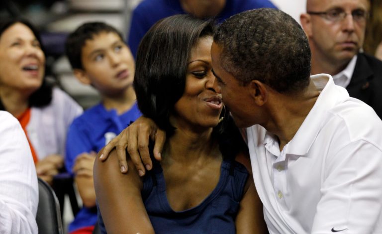 President Barack Obama leans in to kiss first lady Michelle Obama for 'Kiss Cam' while attending Team USA and Brazil in an Olympic exhibition basketball game, Monday, July 16, 2012, in Washington. USA won 80-69. (AP Photo/Alex Brandon)