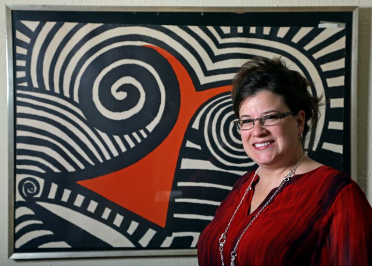   In this Wednesday, Nov. 28, 2012 photo, Karen Mallet stands in front of her Alexander Calder print in her Shorewood, Wis., home. Mallet bought the print for $12.34 at a Goodwill thrift store in Milwaukee. It turned out to be a lithograph by the American artist Alexander Calder worth $9,000. (AP Photo/Morry Gash)  
