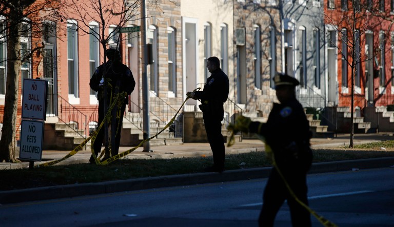 In this Dec. 19, 2018 photo, members of the Baltimore Police Department collect crime scene tape after investigating a shooting scene in Baltimore.