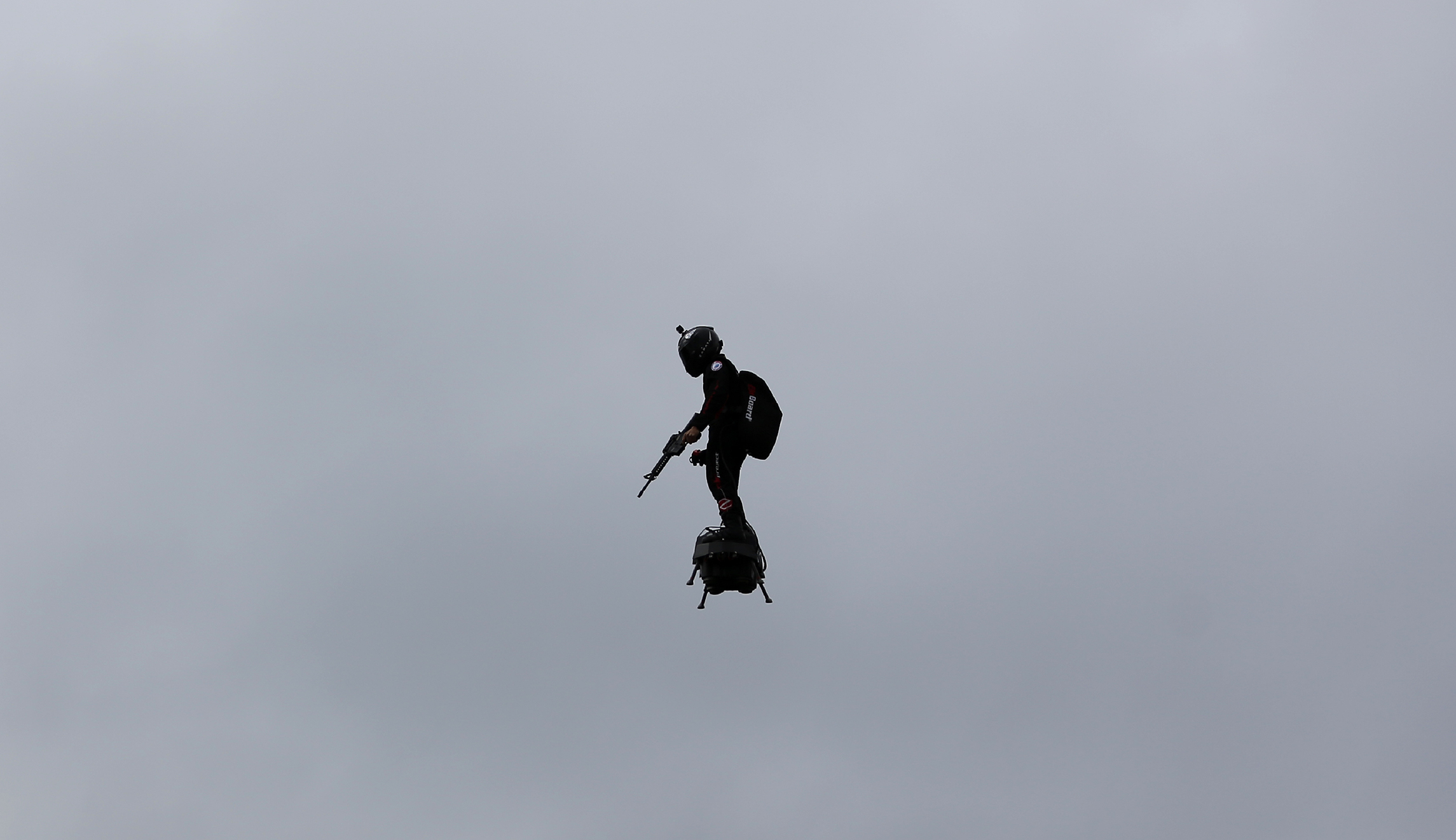 WATCH: French inventor brandishing rifle flies over Paris parade on flyboard