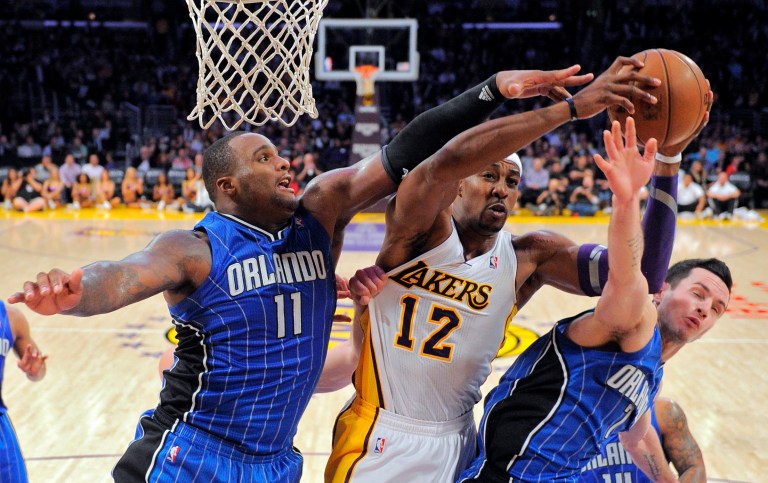   Los Angeles Lakers center Dwight Howard, center, goes up for a shot as Orlando Magic forward Glen Davis, left, and guard J.J. Redick defend during the second half of their NBA basketball game, Sunday, Dec. 2, 2012, in Los Angeles. The Magic won 113-103. (AP Photo/Mark J. Terrill)  