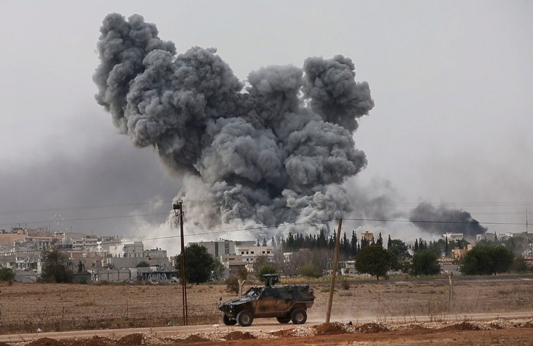 As seen from Mursitpinar in the outskirts of Suruc, at the Turkey-Syria border, a Turkish forces armoured vehicle patrols the border road as in the background thick smoke rises following an airstrike by the US-led coalition in Kobani, Syria as fighting intensified between Syrian Kurds and the militants of Islamic State group, Sunday, Oct. 12, 2014. Kobani, also known as Ayn Arab, and its surrounding areas, has been under assault by extremists of the Islamic State group since mid-September and is being defended by Kurdish fighters. (AP Photo/Lefteris Pitarakis)