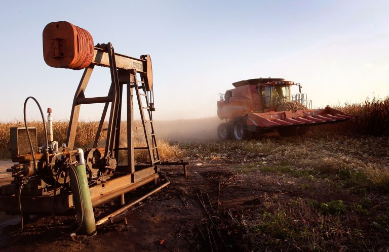 Joe Raben drives his combine past an oil well as he harvests corn on land he farms with his father and uncle on October 4, 2008 near Carmi, Illinois. (Photo by Scott Olson/Getty Images)