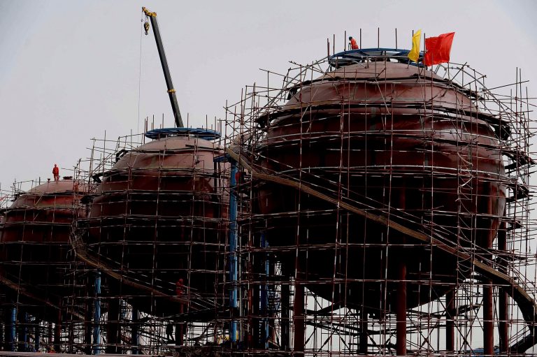 Workers stand on tanks at the Dina oil and gas production zone of PetroChina at the Tarim Basin in northwest China's Xinjiang Uigher Autonomous Region. Facing pressure to overhaul a worn-out growth model, China's leaders are promising dramatic changes at a weekend meeting starting Nov. 9, 2013 that reform advocates hope will make history by unleashing a new wave of economic transformation. (AP Photo)