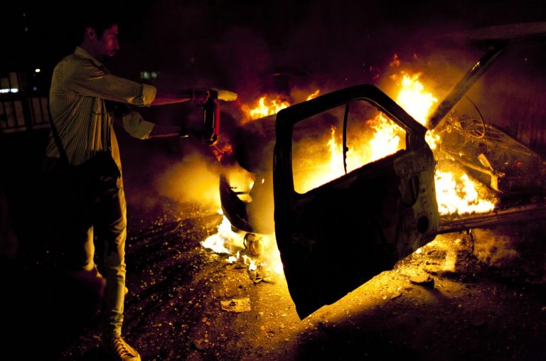 An Egyptian motorist uses a fire extinguisher on police pickup truck that was set on fire by anti-president Mohammed Morsi protesters on the 6th of October bridge, in Cairo, Egypt, Monday, March 4, 2013. In at least two separate incidents in Cairo on Monday, protesters torched two police vehicles, setting them on fire and driving the policemen in the cars running in the middle of traffic on major thoroughfares. (AP Photo/Nasser Nasser)