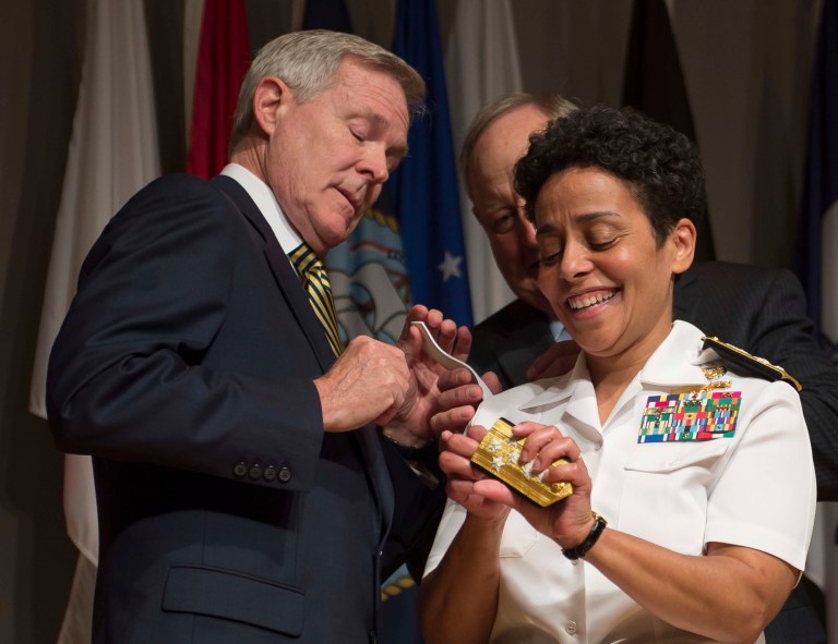 In a Photo provided by the U.S. Navy,  Adm. Michelle Howard, right, lends a hand to Secretary of the Navy Ray Mabus as he and Wayne Cowles, Howard's husband, put four-star shoulder boards on Howard's service white uniform during her promotion ceremony at the Women in Military Service for America Memorial in Washington Tuesday July 1, 2014. Howard is the first woman to be promoted to the rank of admiral in the history of the Navy and will assume the duties and responsibilities as the 38th Vice Chief of Naval Operations from Adm. Mark Ferguson. (AP Photo/ Chief Mass Communication Specialist Peter D. Lawlor)