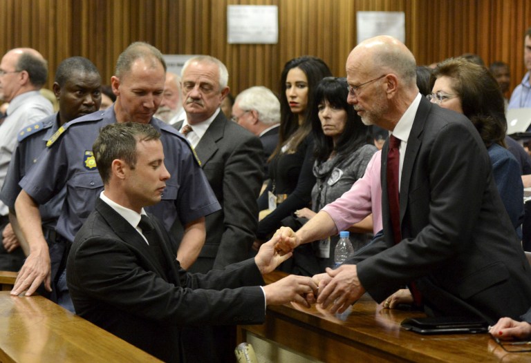 Oscar Pistorius, left front, greets his uncle Arnold Pistorius, right, and other family members as he is led out of court in Pretoria, South Africa, Tuesday, Oct. 21, 2014. Pistorius received a five-year prison sentence for culpable homicide by judge Thokozile Masipais for the killing of his girlfriend Reeva Steenkamp last year (AP Photo/Herman Verwey, Pool)