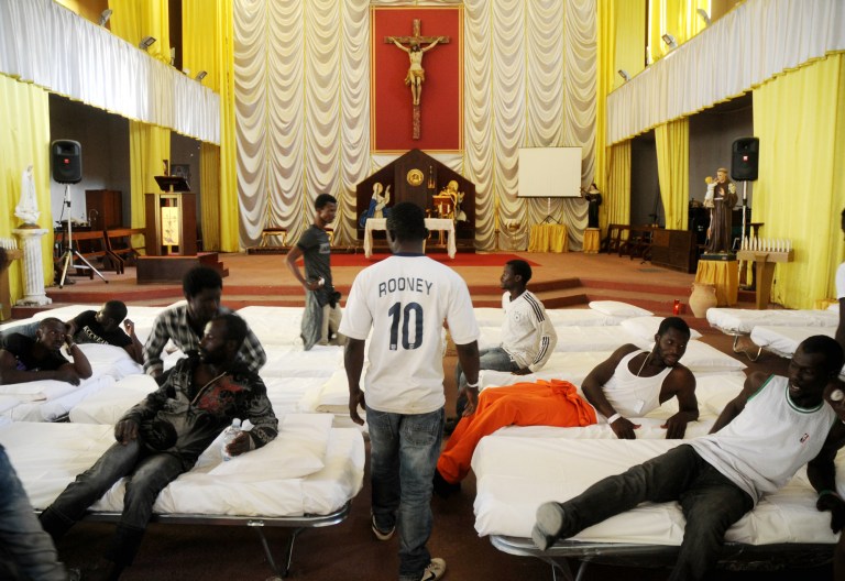 In this picture taken Sunday, June 15, 2014, migrants from Africa are temporarily sheltered in the Catholic church of  St. Curato D'Ars in Palermo, Sicily, Italy. The Italian coast guard and navy have rescued more than 300 migrants whose boats ran into trouble in the Mediterranean Sea and recovered the bodies of 10 migrants whose dinghy had overturned, Sunday. Naval official Salvatore Scimone said 39 survivors on Saturday night had grabbed onto the dinghy until rescuers plucked them to safety aboard another boat. He said he feared that an undetermined number of others were missing in the sea north of Libya. In a separate rescue, three Italian ships took aboard 281 migrants who said they were Syrian and whose fishing boat ran into problems. (AP Photo/Alessandro Fucarini)