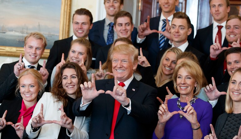President Trump poses for photos with the University of Utah ski team during an event with NCAA championship teams at the White House, Friday, Nov. 17, 2017, in Washington. Education Secretary Betsy DeVos is to the right of the president. (AP Photo/Evan Vucci)