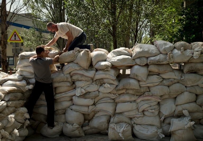 People pile up sand bags to set up a shooting position on the road leading from the airport to Donetsk, Ukraine, Tuesday, May 27, 2014. The eastern city of Donetsk was in turmoil Tuesday a day after government forces used fighter jets to stop pro-Russia separatists from taking over the airport. The mayor said 40 people were killed and went on television to urge residents to stay at home.(AP Photo/Vadim Ghirda)