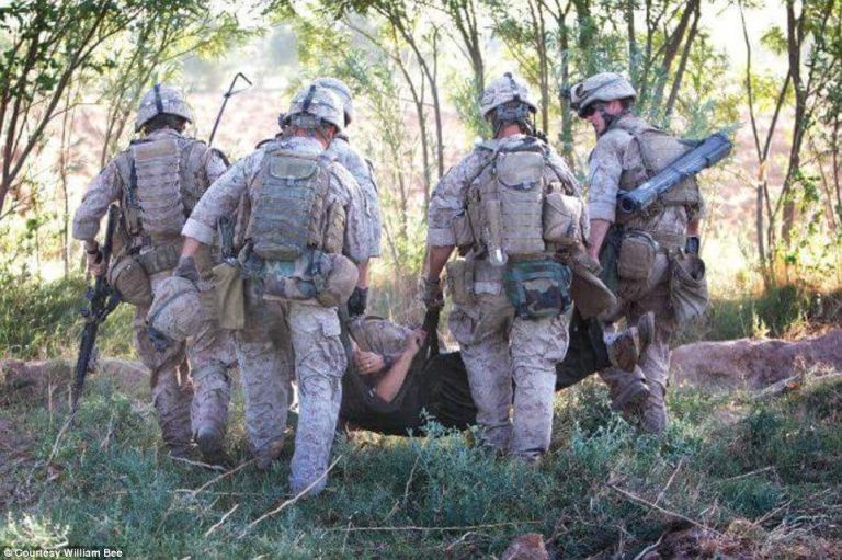 Bill Bee is carried off by squad members after narrowly escaping death from a bomb blast in Afghanistan.