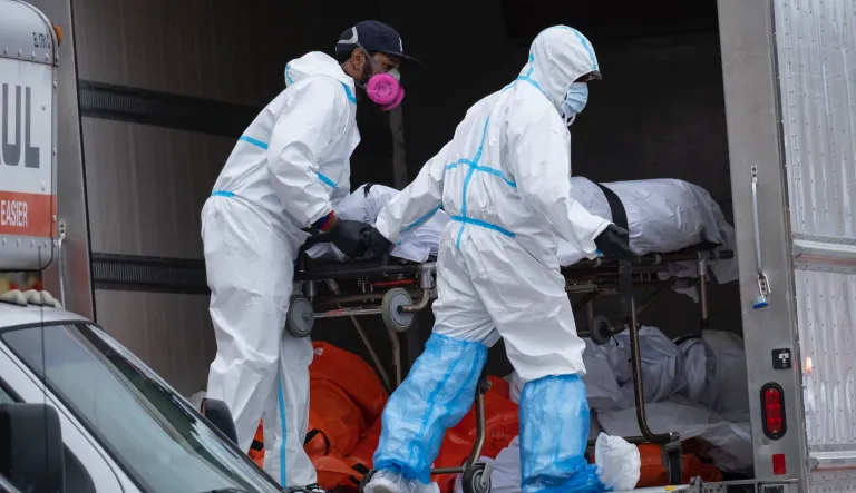 Workers move bodies to a refrigerated truck from the Andrew T. Cleckley Funeral Home in the Brooklyn borough of New York, Wednesday, April 29, 2020. Police responded to a report of human bodies in vehicles, which they determined were connected to the nearby funeral home.