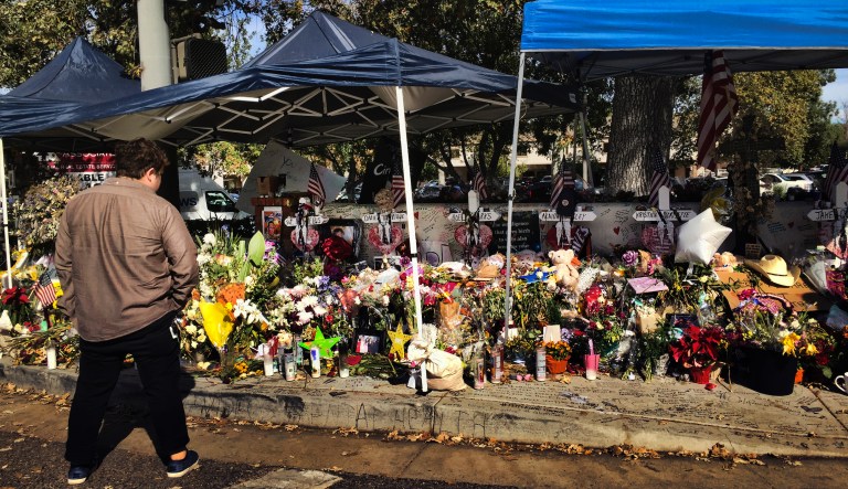 A passerby stops to look over a street side memorial to the shooting victims of the Borderline Bar in Thousand Oaks, Calif. on Tuesday, Nov. 27, 2018. Investigators said Tuesday that the number of victims from a shooting at a country music bar in Southern California this month could have been much higher based on the amount of ammunition the gunman carried.