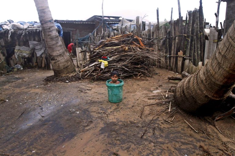 An Indian child sits inside a plastic bucket near his house on the Bay of Bengal coast at Gopalpur, Orissa, about 285 kilometers (178 miles) north east of Visakhapatnam, India, Sunday, Oct. 12, 2014. Trees were uprooted and power cables snapped as a powerful cyclone swept through the Bay of Bengal and slammed into the southern city of Visakhapatnam, one of two storms pounding Asia on Sunday. (AP Photo/Biswaranjan Rout)
