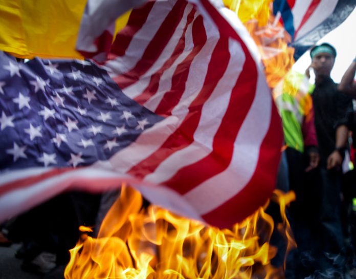 Protesters burn the U.S. flag during a protest in front of American embassy on September 21, 2012 in Kuala Lumpur, Malaysia. (Photo by Rahman Roslan/Getty Images)