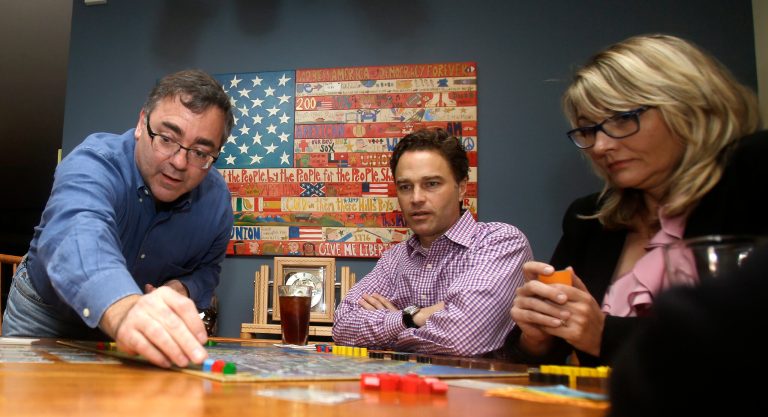 In this photo taken Thursday, Jan. 9, 2014, Spirit Airlines CEO Ben Baldanza center, and DeAnne Gabel, director Investor relations, right, play a game of Power Grid at Baldanza's home, in Fort Lauderdale, Fla. (AP Photo/Alan Diaz)