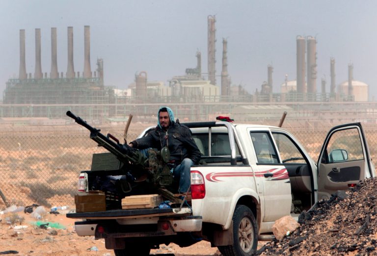 FILE - In this March 5, 2011 file photo, an anti-government rebel sits with an anti-aircraft weapon in front an oil refinery, after the capture of the oil town of Ras Lanouf, eastern Libya. The official Libyan news agency said Sunday, April 6, 2014 that the country's main militia in the east has agreed to hand back control of four oil terminals it captured and shut down last summer in its demand for a share in oil revenues. The shutdown has cost Libya millions of dollars. (AP Photo/Hussein Malla, File)