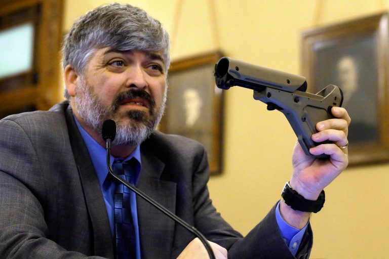 In this Feb. 2013 photo, Todd Vandermyde with the NRA shows off a gun butt stock during a House Committee hearing on assault weapons at the Illinois State Capitol in Springfield Ill. The Senate has a Concealed Carry bill that maybe a compromise between Chicago lawmakers fighting street violence and downstate moderates who want easier access to guns. The legislation would require applicants statewide to be of 