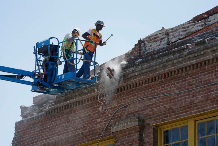 Contractors pull loose bricks from the roof of an earthquake damaged 36,000 square foot former boat shop on Mare Island Tuesday, Aug. 26, 2014, in Vallejo, Calif. The building dates from 1904 and was used by the Navy. The bayside city that twice was briefly the capital of California sustained more than $5 million in damage and dozens of injuries. It was the latest blow to a town that has weathered years of bankruptcy and is now beset by gangs and crime. (AP Photo/Eric Risberg)