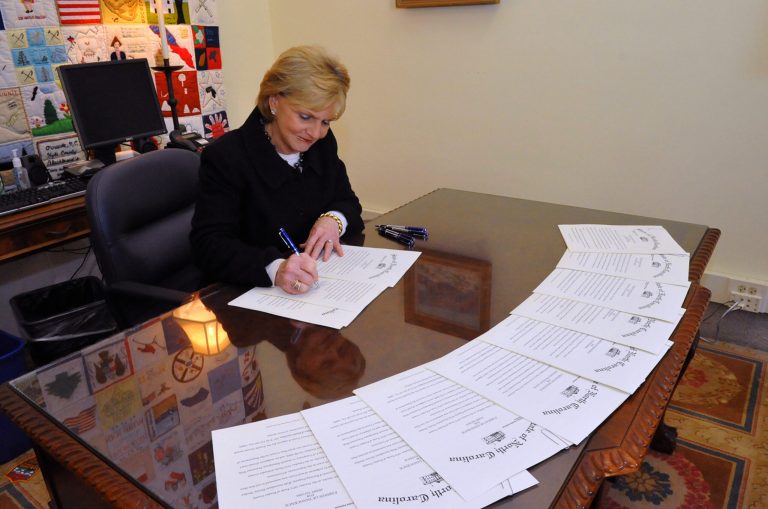   In a photo provided by the Office of the governor, outgoing North Carolina Gov. Beverly Perdue signs pardons Monday, Dec. 31. 2012 to the Wilmington 10, a group wrongly convicted 40 years ago in a notorious Civil Rights-era prosecution that led to accusations of the state holding political prisoners. Perdue issued pardons of innocence Monday for the nine black men and one white woman who combined were sentenced to nearly 300 years in prison for the 1971 firebombing of a Wilmington grocery store after police shot a black teenager. The pardon means the state no longer thinks the 10 _ four of whom have since died _ committed a crime. (AP Photo/North Carolina Governors Office)  