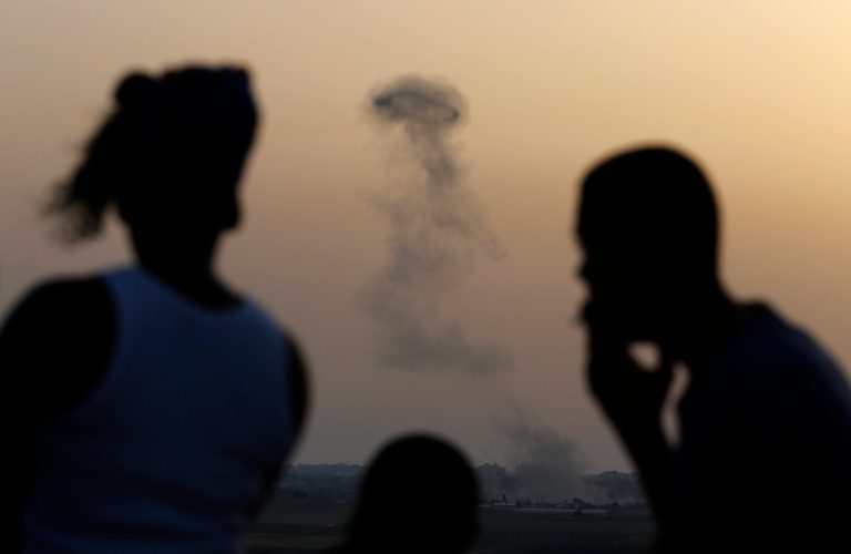 Israelis stand on a hill at the Israeli town of Sderot, overlooking the Gaza Strip, as they watch smoke rising following an Israeli strike on Gaza, Saturday, July 12, 2014.  Ignoring international appeals for a cease-fire, Israel on Saturday widened its range of Gaza bombing targets to civilian institutions with suspected Hamas ties and announced it would hit northern Gaza 