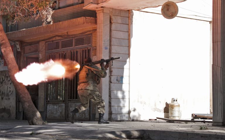 An Afghanistan's National Army (ANA) soldier fires his weapon at the site of a clash between insurgents and security forces over Indian Consulate in Herat, Afghanistan, Friday, May 23, 2014. Gunmen armed with machine guns and rocket-propelled grenades attacked the Indian Consulate in western Afghanistan's Herat province Friday, an assault that injured no diplomatic staff, police said. Indian officials said there had been a threat against its diplomats in Afghanistan, but gave no other details. (AP Photo/Hoshang Hashimi)