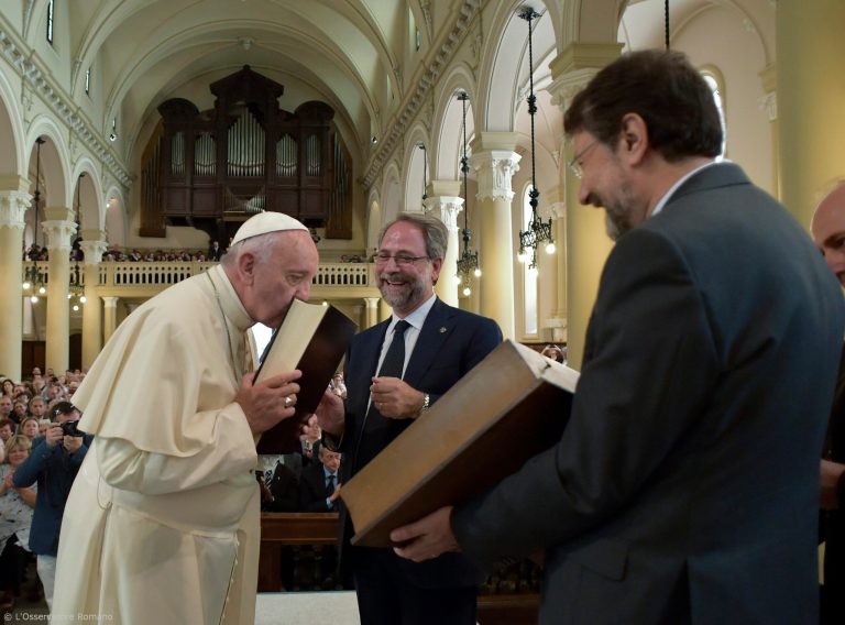 Pope Francis kisses an ancient copy of the Bible he was presented by Eugenio Bernardini, center, the Moderator of the Waldensian Church, during the first ever visit of a pope to the Waldensian evangelical church, in Turin, northern Italy, Monday, June 22, 2015. (L' Osservatore Romano/Pool Photo via AP)