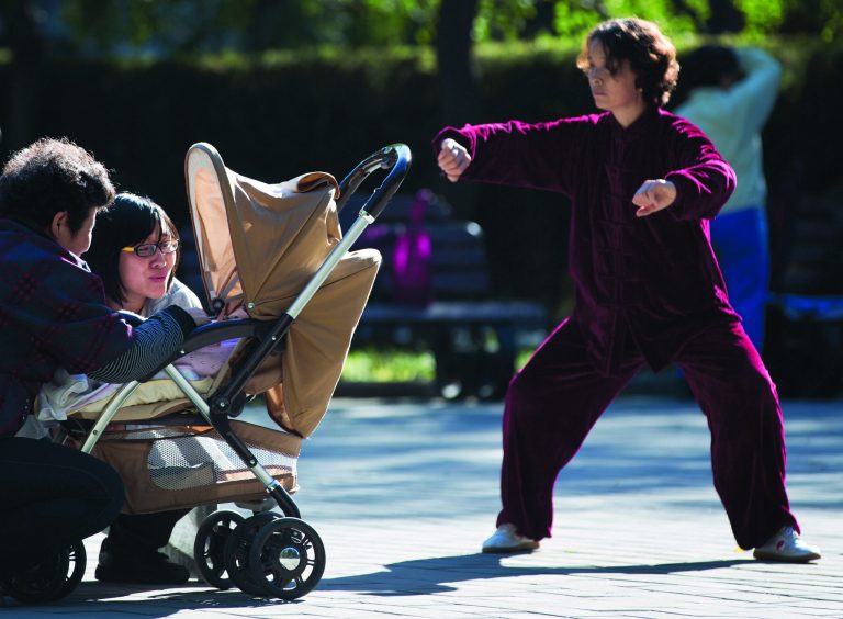 A Chinese woman performs a morning exercise next to a family members having a light moment with their infant at the Ritan Park in Beijing Wednesday, Oct. 31, 2012. A government think tank says China should start phasing out its one-child policy immediately and allow two children for every family by 2015. It remains unclear whether Chinese leaders are ready to take that step. (AP Photo/Andy Wong)