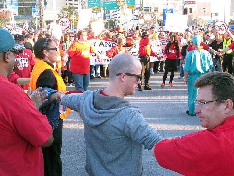 Casino workers link hands as they occupy an intersection and block traffic in Atlantic City N.J. on Wednesday Oct. 8, 2014. They were protesting givebacks demanded by the owners of the Trump Taj Mahal Casino Resort in return for keeping the casino open. The company wants to eliminate employee health care and pension plans. Police arrested 24 protesters.(AP Photo/Wayne Parry)