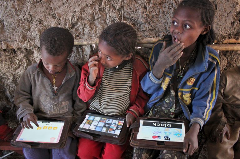  In this photo taken Tuesday, Nov. 27, 2012, children play with tablet computers given to them by the One Laptop Per Child project in the village of Wenchi, Ethiopia. The project gave tablets to the children in the poor, illiterate village to see how much the children could teach themselves and now many kids can recite the English alphabet and spell words in English. (AP Photo/Jason Straziuso)  