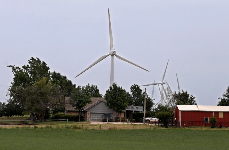 In this July 28, 2014 photo, the home of Tammy and Rick Huffstutlar is surrounded by wind turbines in Calumet, Okla. A decade ago, states offered wind-energy developers an open-armed embrace, envisioning a bright future for an industry that would offer cheap electricity, new jobs and steady income for large landowners. Today, many of the same political leaders who initially welcomed the wind industry want to regulate it more tightly.   (AP Photo/Sue Ogrocki)
