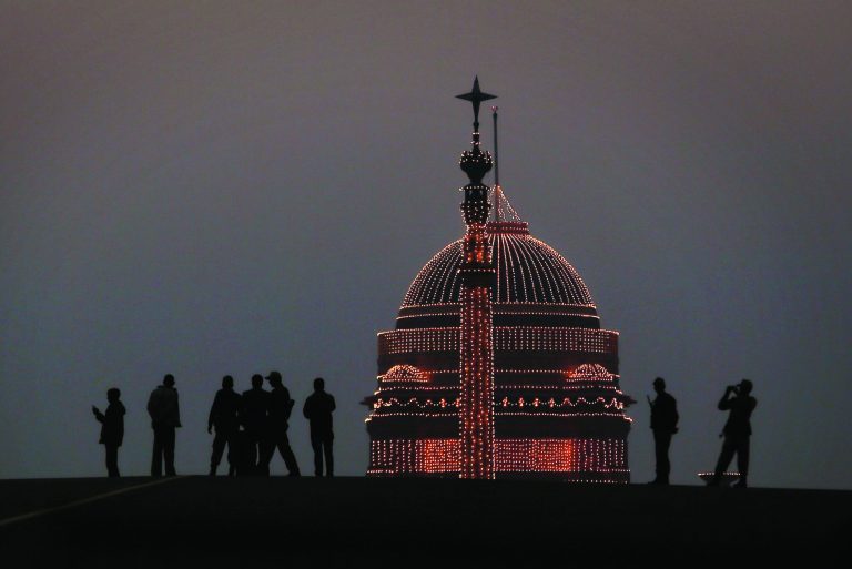 Indians walk past the Presidential Palace, illuminated to mark Republic Day in New Delhi, India , Saturday, Jan. 26, 2013. Indians across the country celebrated Republic Day, which commemorates the 1950 adoption of its constitution. (AP Photo/Manish Swarup)