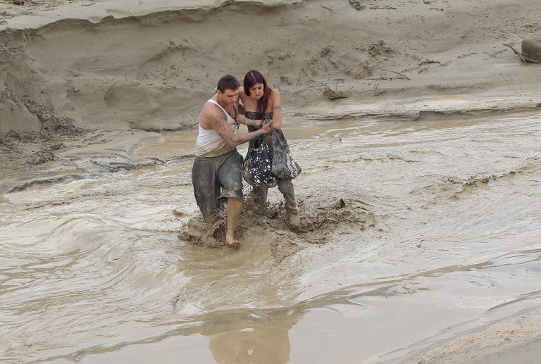 Mike Garcia, left, helps a friend cross the road in Thousand Palms, Calif., after floodwaters surged Monday, Sept. 8, 2014. Moisture from former Hurricane Norbert streamed through Southern California on Monday, flooding roads and highways and leaving dozens of cars stranded  in inland and desert areas. (AP Photo/The Desert Sun, Jay Calderon)  RIVERSIDE PRESS-ENTERPRISE OUT;  NO SALES; NO FOREIGN