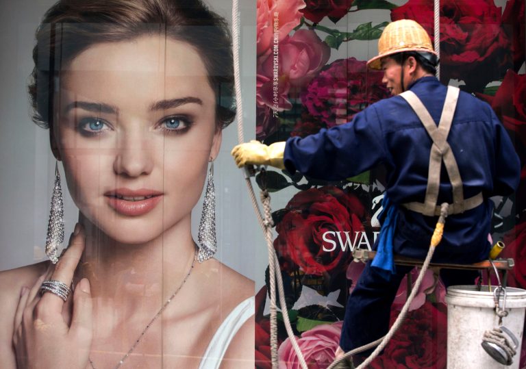 A window cleaner moves past an advertisement for a jewelry boutique in Beijing on Thursday, April 10, 2014. China reported an unexpected contraction in exports in March, raising the danger of job losses as Beijing tries to overhaul its slowing economy. 