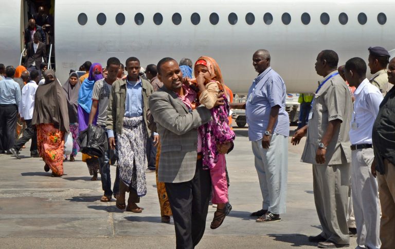 Somali Member of Parliament Muse Sheikh Omar, center, carries a young Somali girl deportee as he helps Somalis who had been deported from Kenya to Somalia from their aircraft after it landed at the airport in Mogadishu, Somalia, Wednesday, April 9, 2014. Kenya's security minister said Wednesday that 82 Somali nationals have been deported in an ongoing security crackdown following recent terror attacks in Kenya's capital and the port city of Mombasa. (AP Photo/Farah Abdi Warsameh)