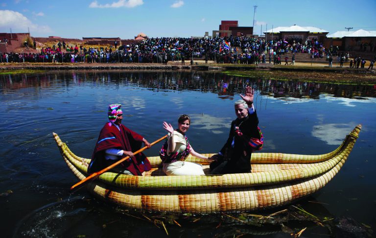 Newlyweds Bolivia's Vice President Alvaro Garcia Linera, right, and bride Claudia Fernandez, center, wave from an Aymara reed raft known as a 