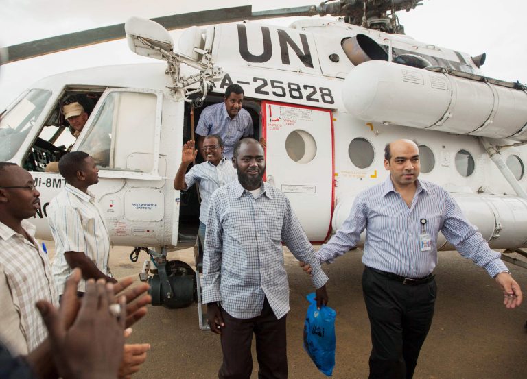 A member of the joint U.N. African Union Mission in Darfur (UNAMID), right, escorts three freed humanitarian workers out of a U.N. helicopter as they landed in El Fasher, North Darfur, Sudan, Saturday, July 19, 2014. The international peacekeeping mission in Sudan's Darfur region said three aid workers have been freed after over a month in captivity. The mission said the three were among 25 humanitarian workers abducted by armed men in North Darfur on June 18. The statement says 20 were released on the same day and two others were freed two weeks later. (AP Photo/Albert Gonzalez Farran, UNAMID)