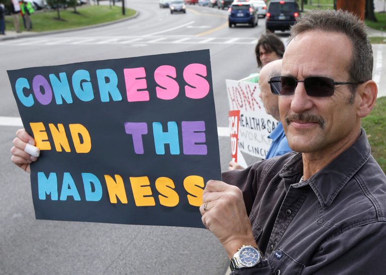 Steven Ahrenholz, a furloughed federal worker, protests outside the Department of Health and Human Services CDC offices, Tuesday, Oct. 15, 2013, in Cincinnati. (AP Photo/Al Behrman)