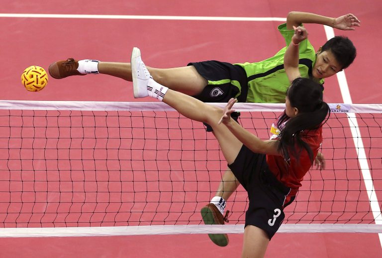 Myanmar's Phyu Phyu Than, top, kicks a ball as Laos player Koy Xayavong, front, blocks during the women's doubles sepak takraw final match at the 17th Asian Games Monday, Sept. 22, 2014 in Incheon, South Korea. (AP Photo/Eugene Hoshiko)