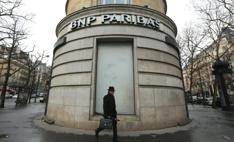 FILE - In this Feb. 5, 2013 file photo, a man walks past the French bank BNP Paribas headquarters in Paris. French economy minister Arnaud Montebourg on Monday, June 23, 2014 is urging U.S. authorities to be 