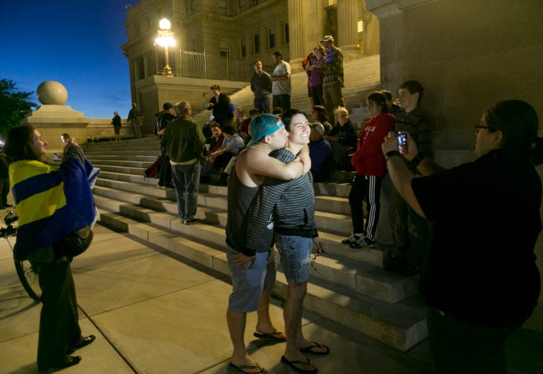 Mike Chase, center left, kisses his partner Matthew Montoya on the steps of the Idaho Statehouse during a rally in support of same sex marriage in Boise on Tuesday night May 13, 2014. U.S. Magistrate Judge Candy Dale ruled earlier in the day that Idaho's ban on gay marriage is unconstitutional. (AP Photo/The Idaho Statesman, Kyle Green)
